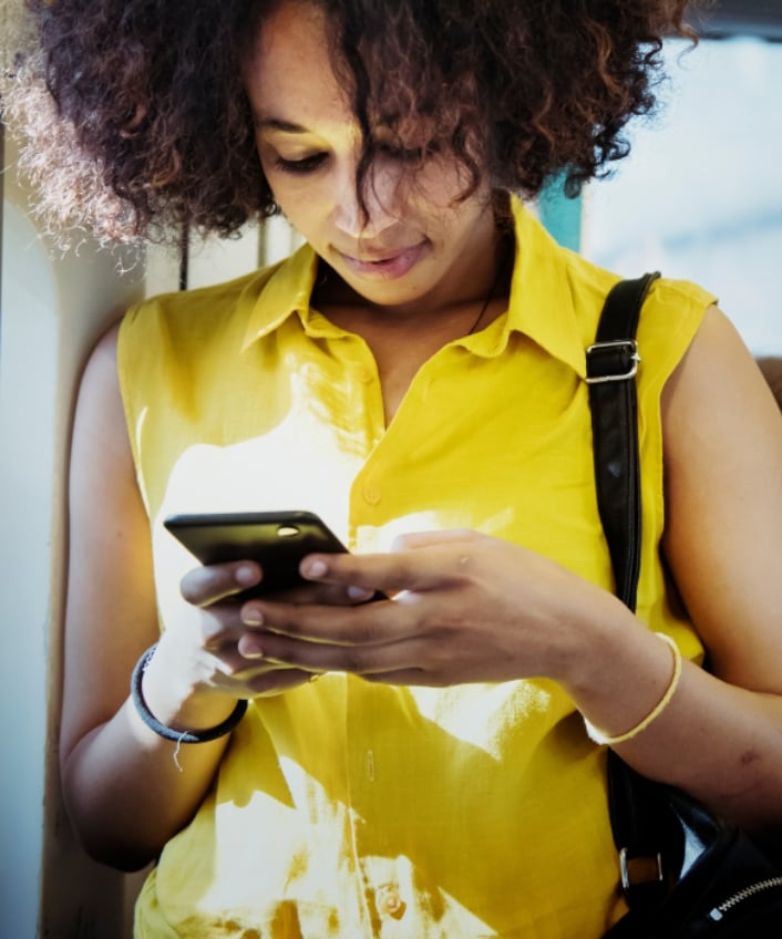 A woman looks down at her phone in order to install a general software update while riding the bus.