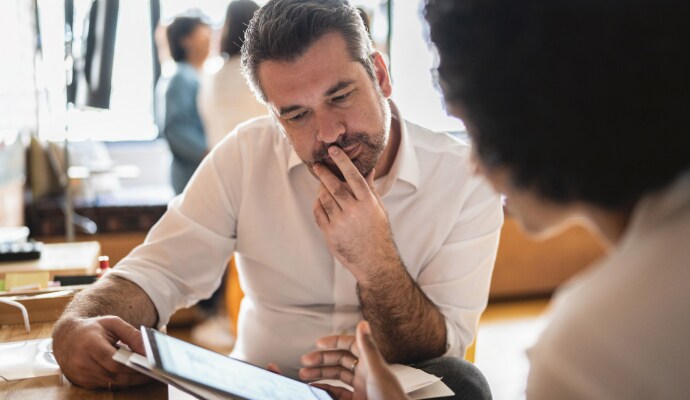 Man looking at another man who is using a laptop