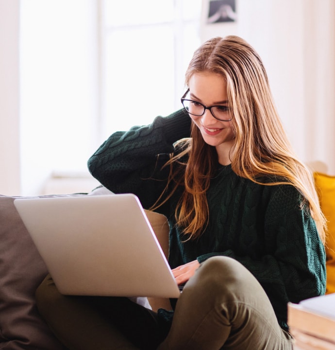 girl on sofa using laptop launching Norton 360 Standard.